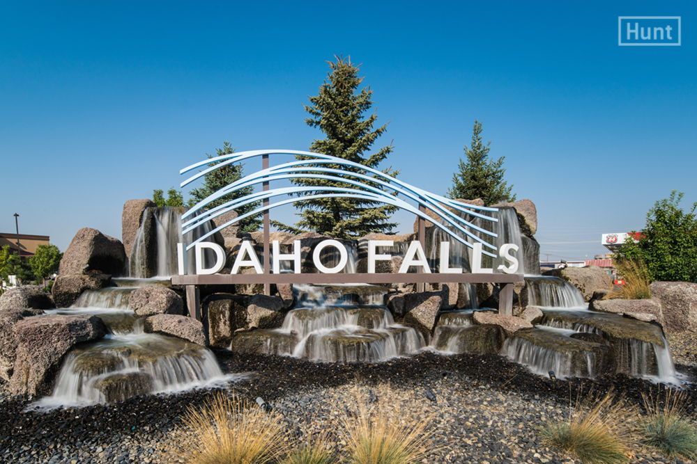 Idaho Falls sign with waterfalls and trees in the background