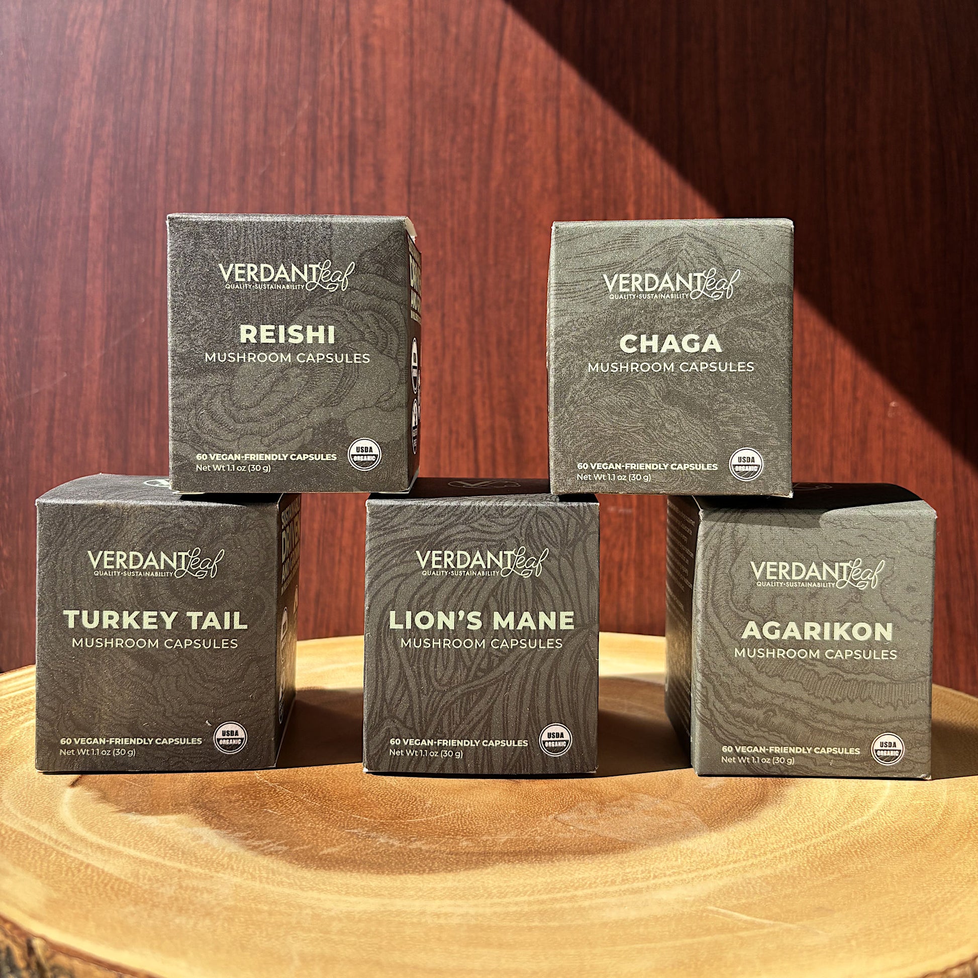 Five boxes of Verdant mushroom capsules on a wooden surface with a wooden background